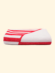 Modèle "Crassa" de Tucca, serviette de plage légère 100% coton biologique, parfaitement pliée comme présentée sur l'emballage. Montrant que c'est une serviette de plage très chose facile à transporter.