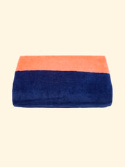 Modèle "Konoh" de serviette de plage Tucca 100% coton biologique, parfaitement pliée comme présentée sur l'emballage, avec deux épingles de chaque côté, celles qui peuvent être utilisées pour fixer votre serviette de plage au sable.