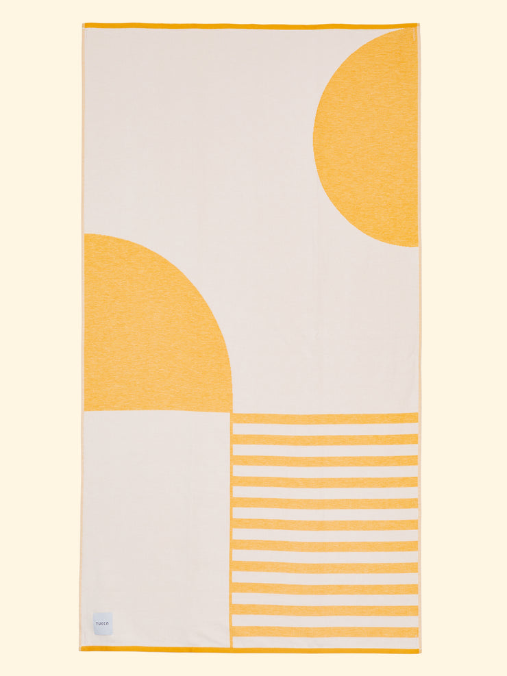 Tucca "Danai" extra light beach towel extended. Light mustard yellow and white colors in big blocks composing a beautiful design. Large beach towel that doesn't get blown by the wind. Super soft texture as it is made with 100% organic cotton.